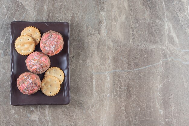 Glazed cookies and cracker on a platter on marble.