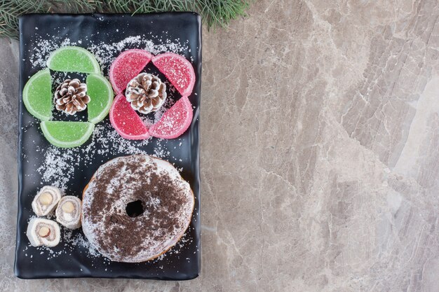 Glazed donut, turkish delights and marmelades on a platter on marble. 