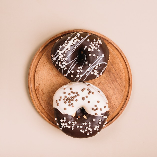 Free photo glazed donuts on wooden board on table