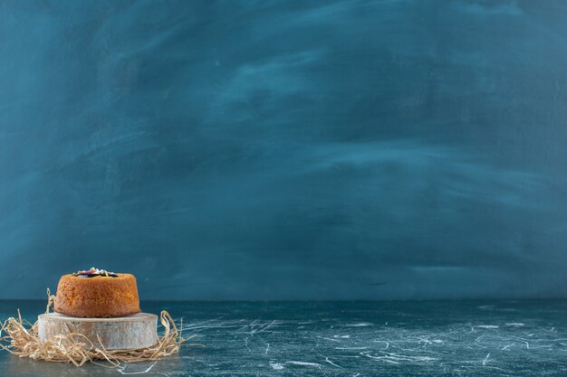 青の背景に、ボード上の艶をかけられたミニケーキ。高品質の写真