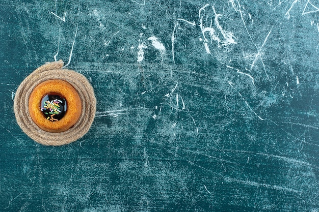 Glazed mini cake on a trivet, on the blue table. 