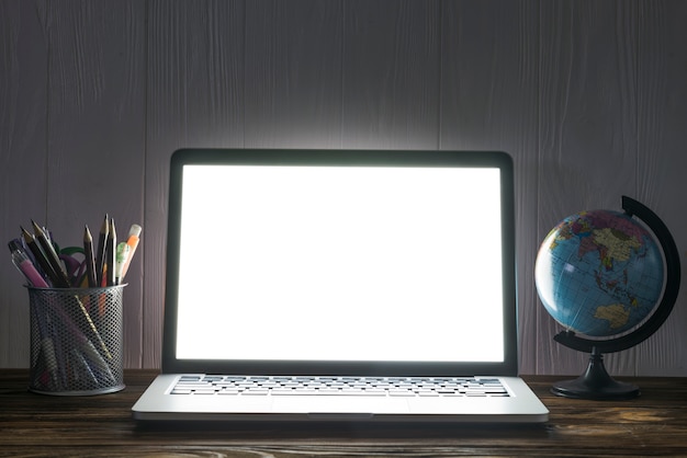 Globe and stationery near laptop