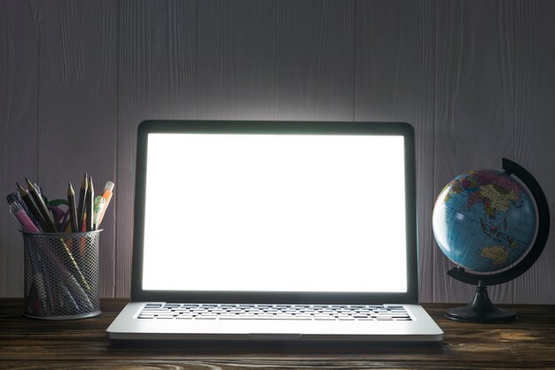 Globe and stationery near laptop