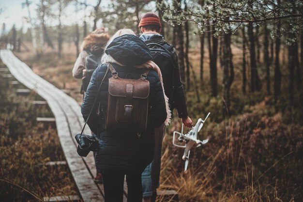 In gloomy autumn day group of friends are hiking in nice park, man is holding a drone.