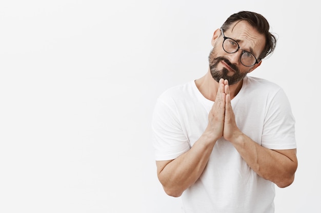 Gloomy and clingy bearded mature man with glasses posing