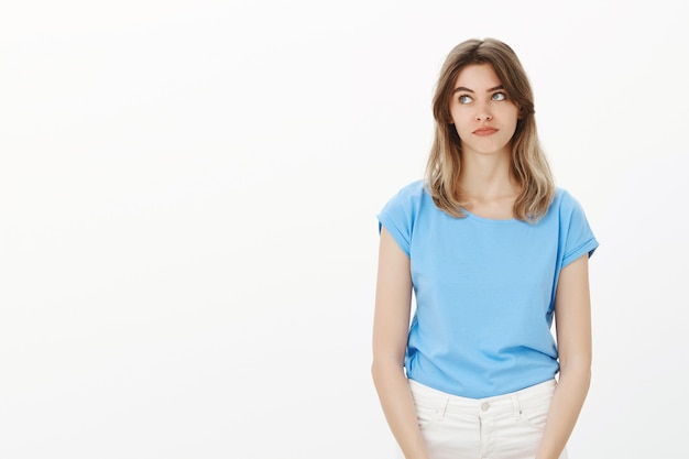 Gloomy and indecisive blond woman looking left with bored face