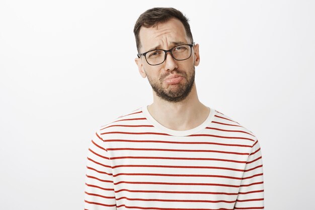 gloomy man with beard in glasses, pouting and crying, complaining to friend about boyfriend who forgot about anniversary