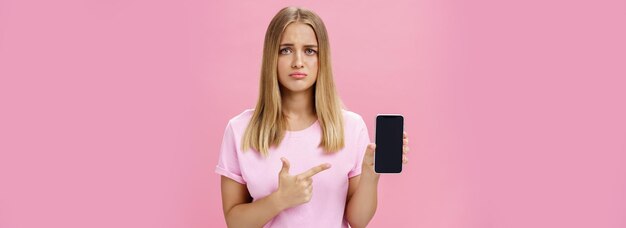 Free photo gloomy and sad cute young female showing friend negative feedback about her project in internet