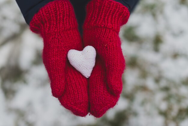 Gloved hands holding a white heart