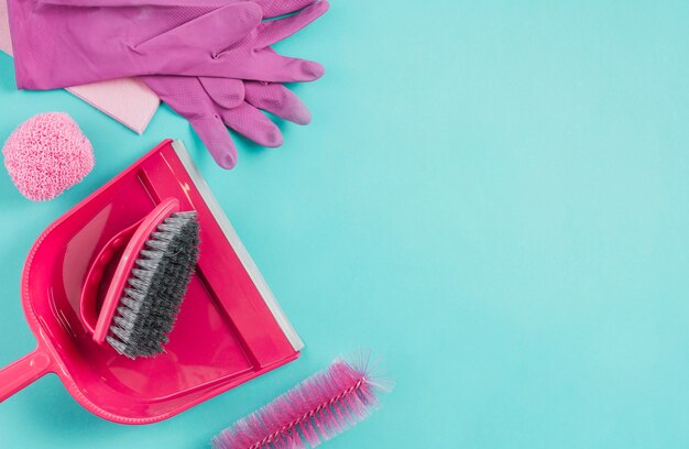 Gloves, dustpan, scrub and brush on turquoise background