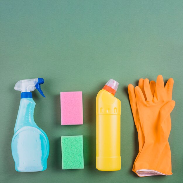 緑の背景に手袋、スポンジ、プラスチックボトル