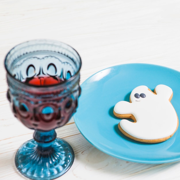 Goblet and ghost cookie on wooden table