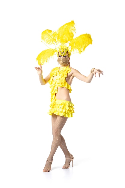 Going on. Beautiful young woman in carnival, stylish masquerade costume with feathers dancing on white studio background. Concept of holidays celebration, festive time, dance, party, having fun.