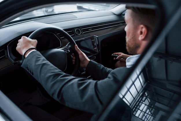 Идти вперед. Прекрасная успешная пара пробует новую машину в автомобильном салоне