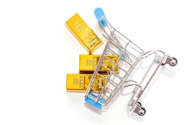 Gold bars in a shopping cart on a white background with copy space. view from above.