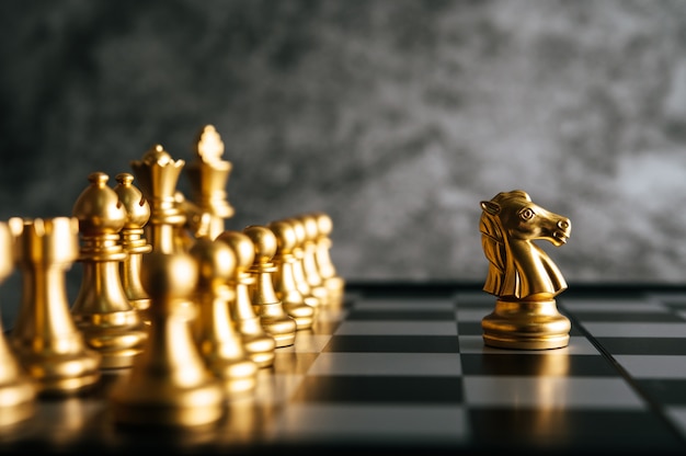 Золотые шахматы на шахматной настольной игре для концепции лидерства в метафоре бизнеса