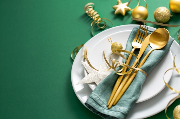 Золотые столовые приборы подаются на тарелку на Рождественский ужин