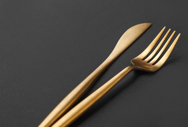 Gold cutlery set on black background