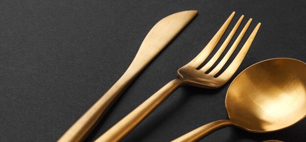 Gold cutlery set on black background