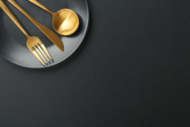 Gold cutlery set on black background