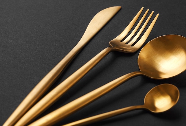 Gold cutlery set on black background