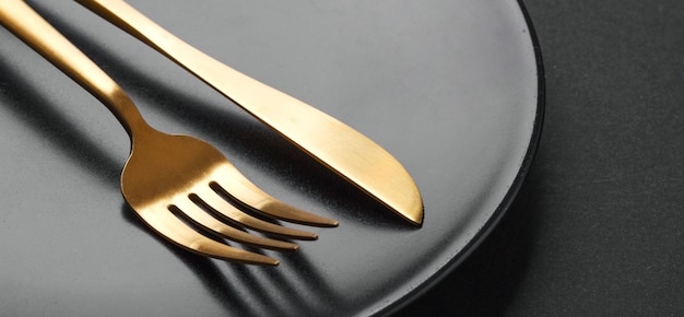 Gold cutlery set on black background