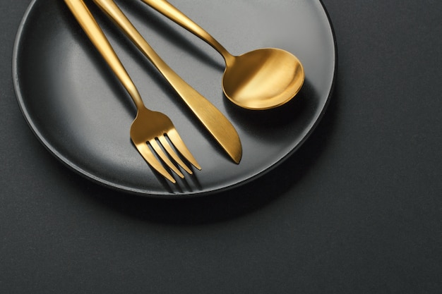 Gold cutlery set on black background