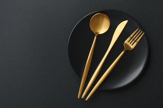 Gold cutlery set on black background