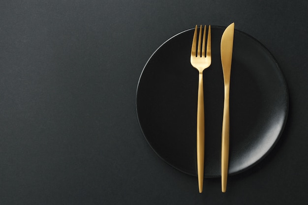 Gold cutlery set on black background