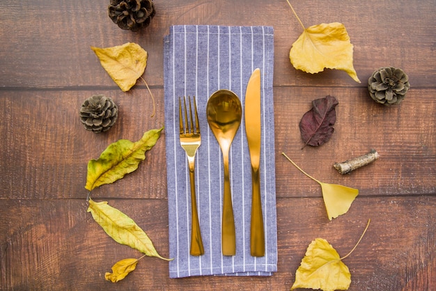 Gold cutlery set on striped napkin with strobiles