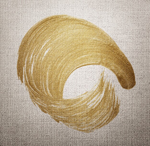 Free photo gold oil paint brush stroke texture on a brown fabric textured background