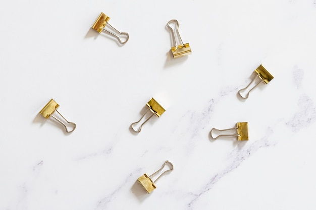 Gold paper clips on plain background