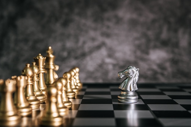 Золотые и серебряные шахматы на шахматной настольной игре для концепции лидерства в метафоре бизнеса