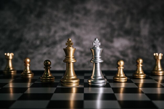 Золотые и серебряные шахматы на шахматной настольной игре для концепции лидерства в метафоре бизнеса