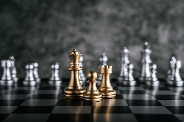 ビジネスメタファーリーダーシップコンセプトのチェスボードゲームで金と銀のチェス