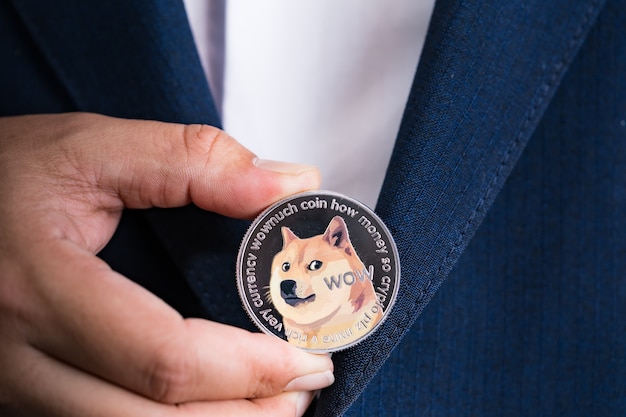Golden bitcoin coin dogecoin doge group included with cryptocurrency on hand business man wearing a blue suit. filed and put and give to me. close up and macro photography concept.