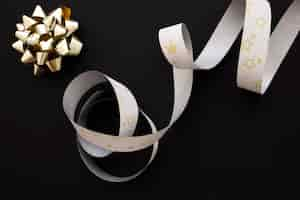 Free photo golden bow and silver star shape silver ribbon on black background