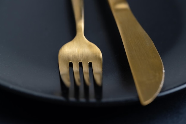 Golden cutlery on plate on dark