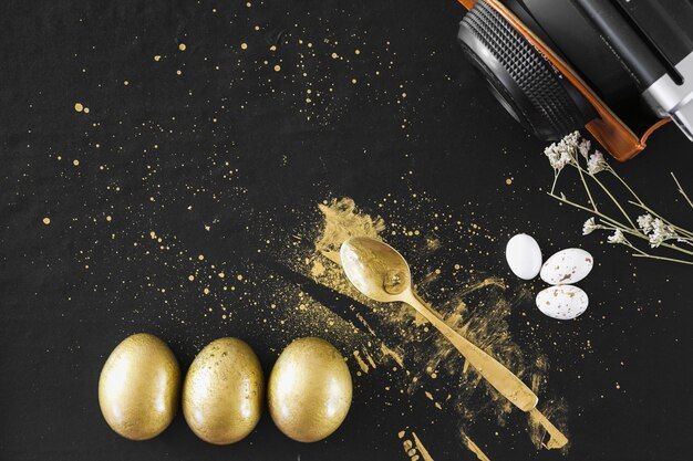 Golden eggs near spoon and camera