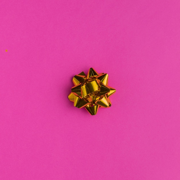 Golden gift bow on bright pink background