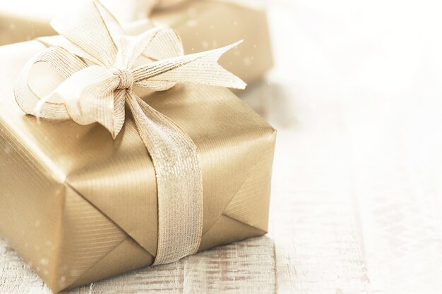 Golden gift boxes with beautiful ribbon and bow on a bright shiny background, holiday concept, horizontal with copy space