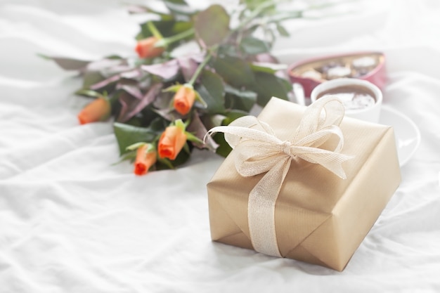 Free photo golden gift package with a bouquet of flowers and chocolates