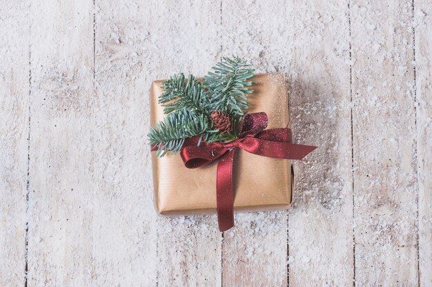 Golden gift with a red bow and pine leaves