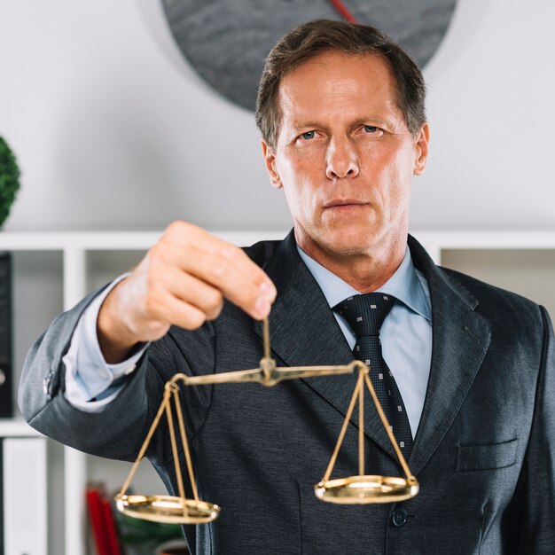 Golden justice scale behind the lawyer signing the document on desk