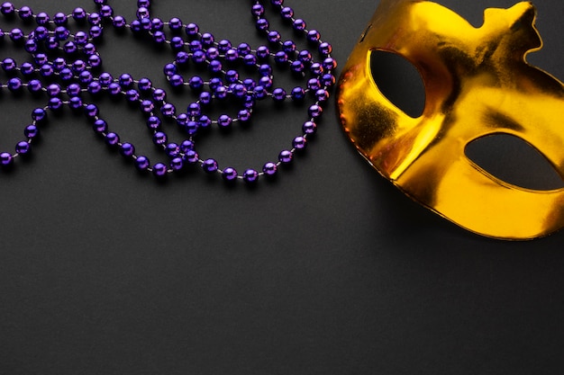 Free photo golden mask and violet pearls high view