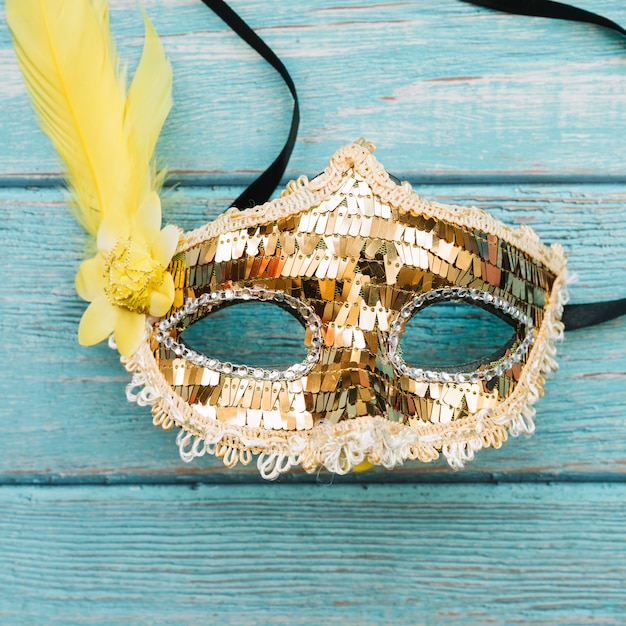 Golden mask with sequins and feather