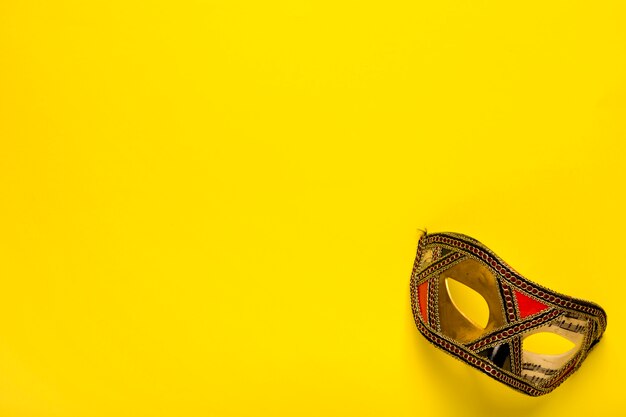 Golden mask on yellow background with copy space