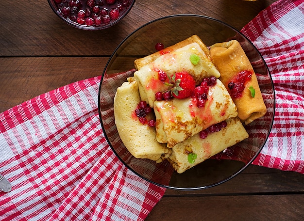 Golden pancakes with cranberry jam and honey in a rustic style. Top view