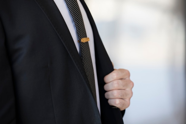 Free photo golden pin on the tie of a man in a suit.