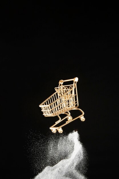 Golden shopping cart in white glitter on black background